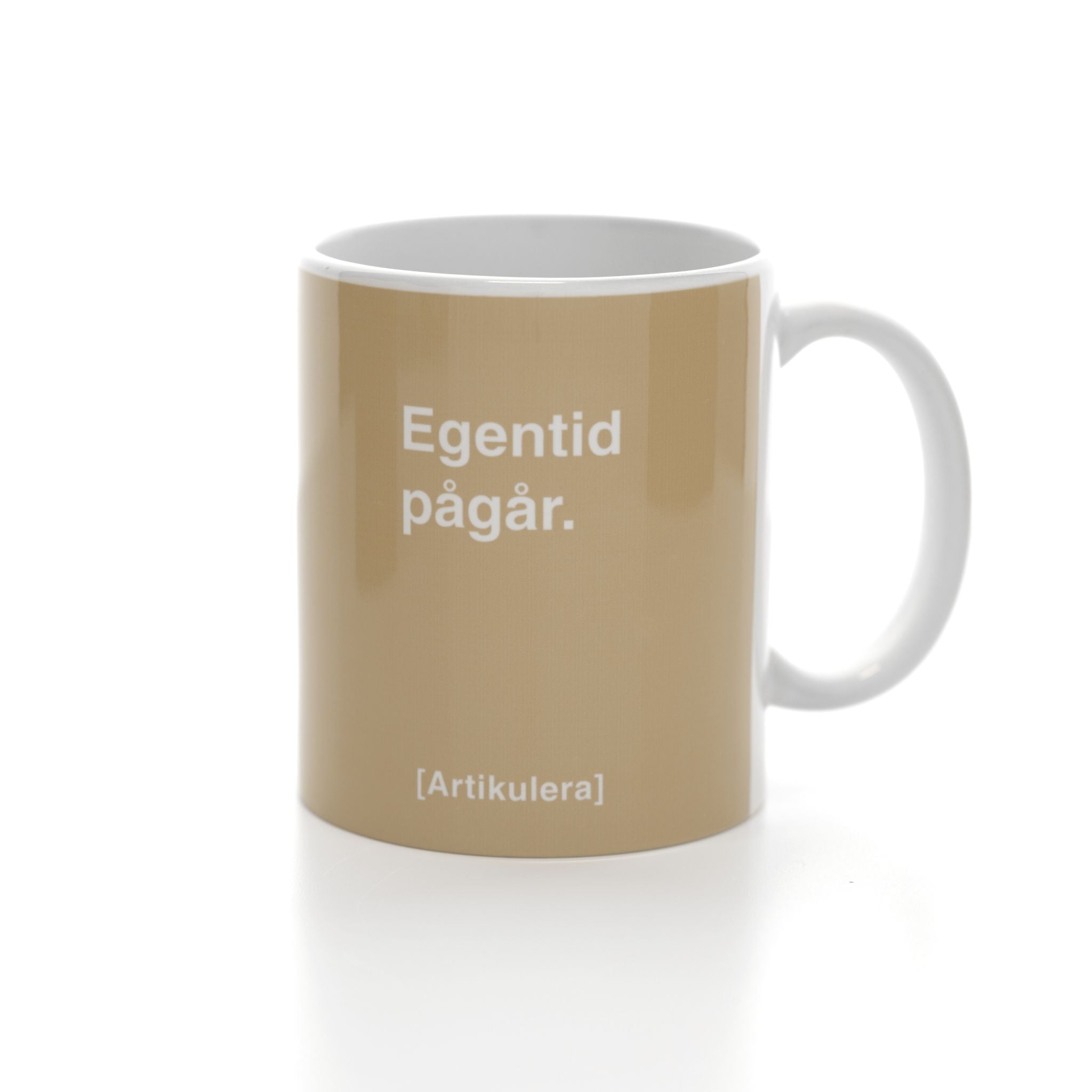 Vit mugg med beige tryck, vit text ”Egentid pågår.” samt vit Artikulera-logotyp
