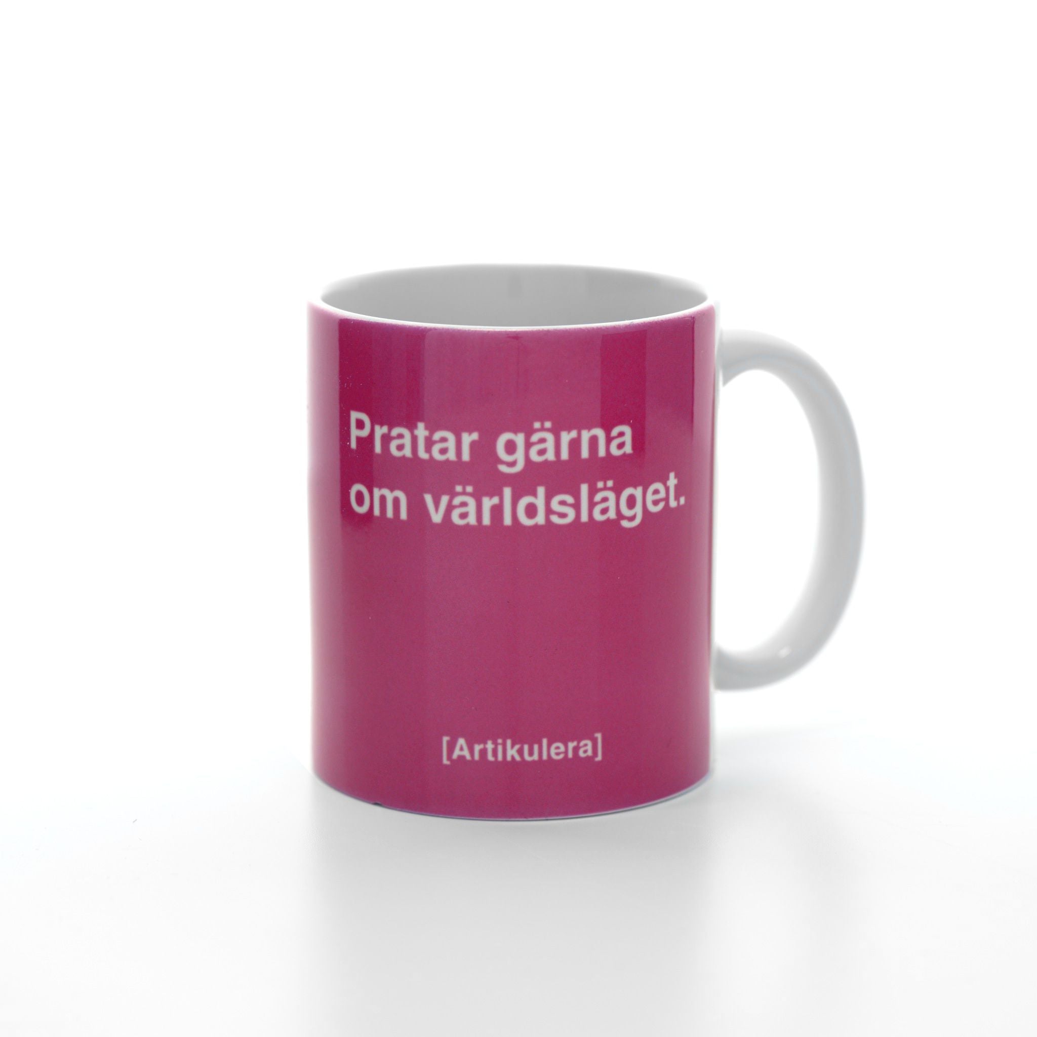 Vit mugg med cerise tryck, vit text ”Pratar gärna om världsläget.” samt vit Artikulera-logotyp