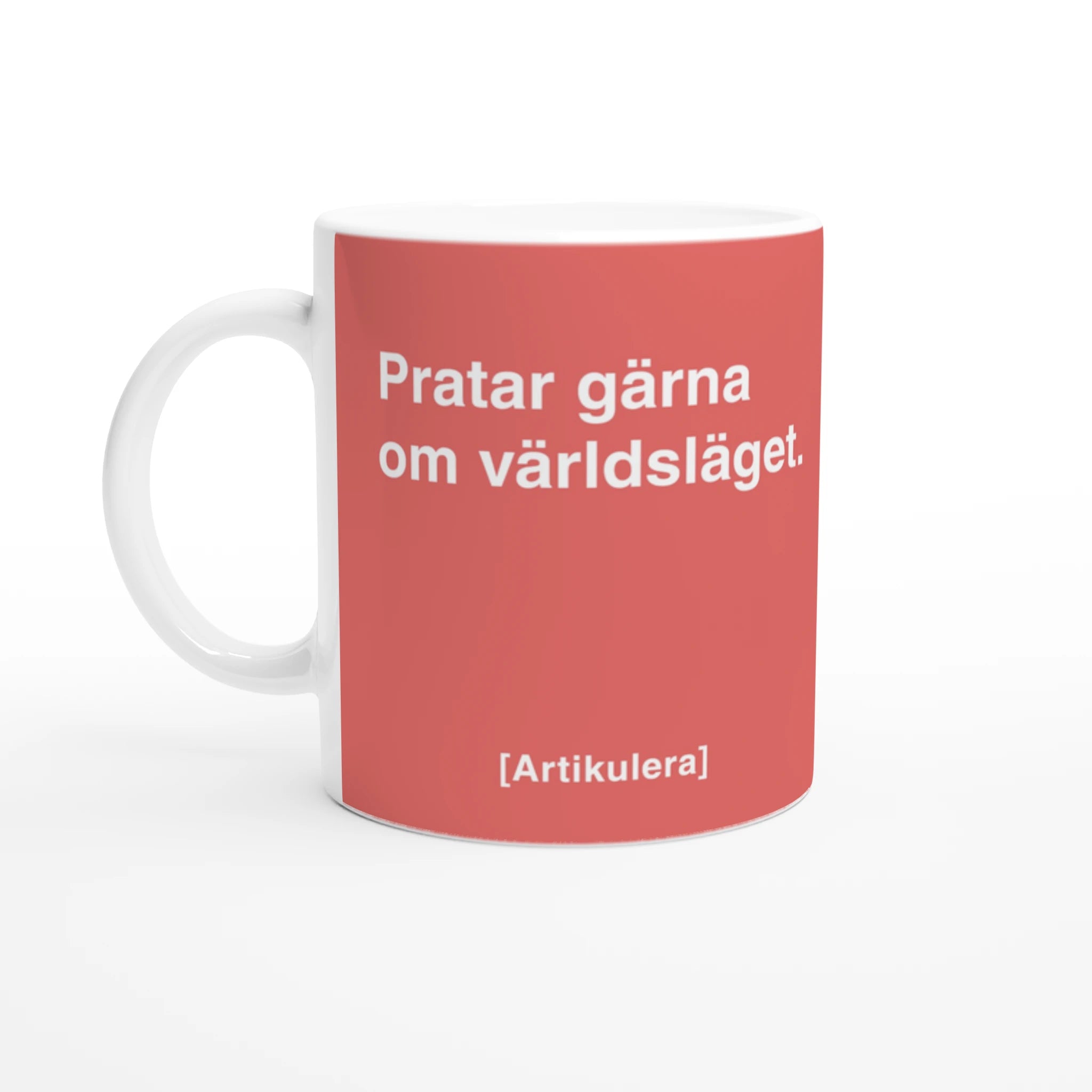 Vit mugg med korallrött tryck, vit text ”Pratar gärna om världsläget.” samt vit Artikulera-logotyp