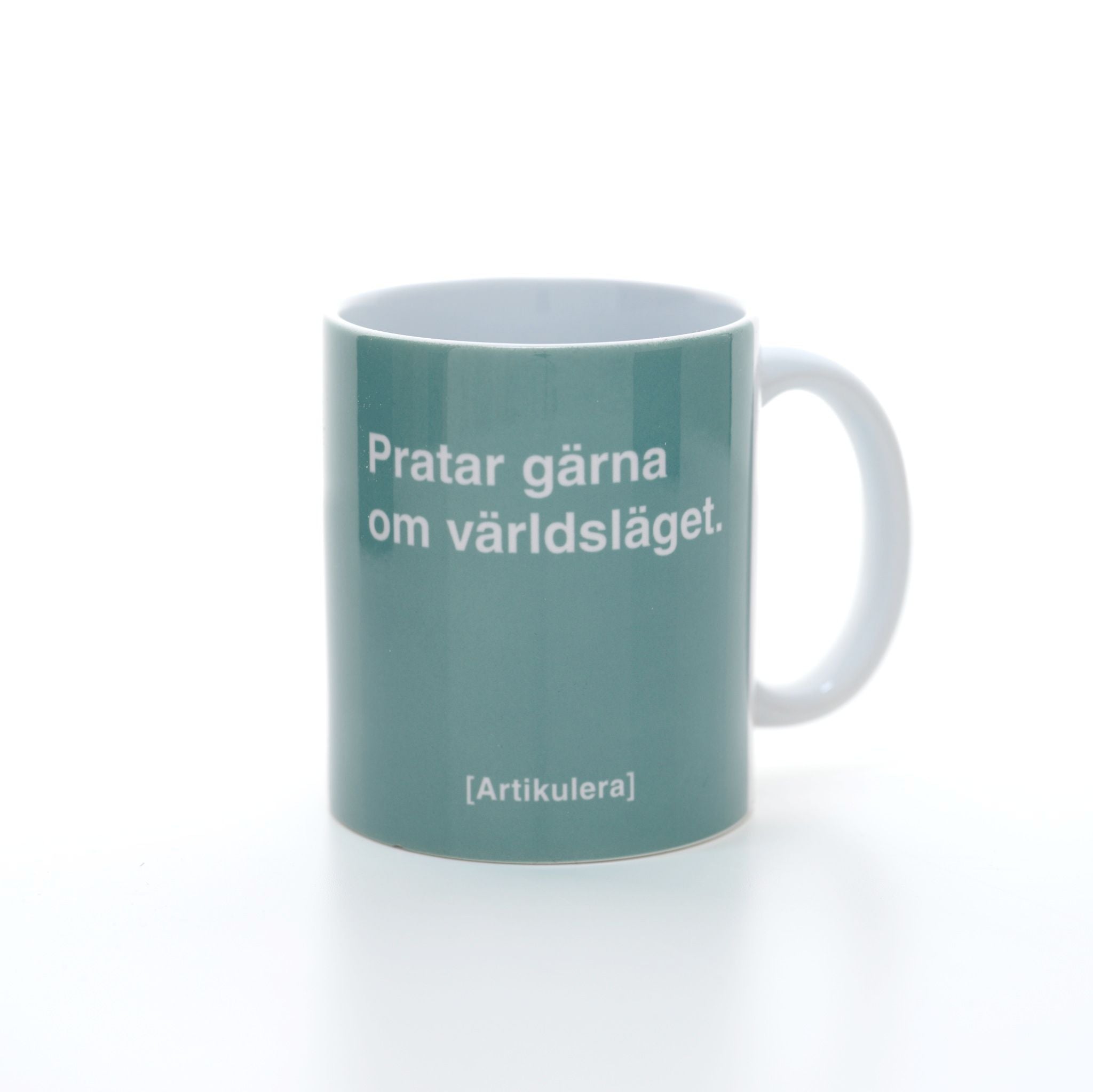 Vit mugg med ljus blågrönt tryck, vit text ”Pratar gärna om världsläget.” samt vit Artikulera-logotyp