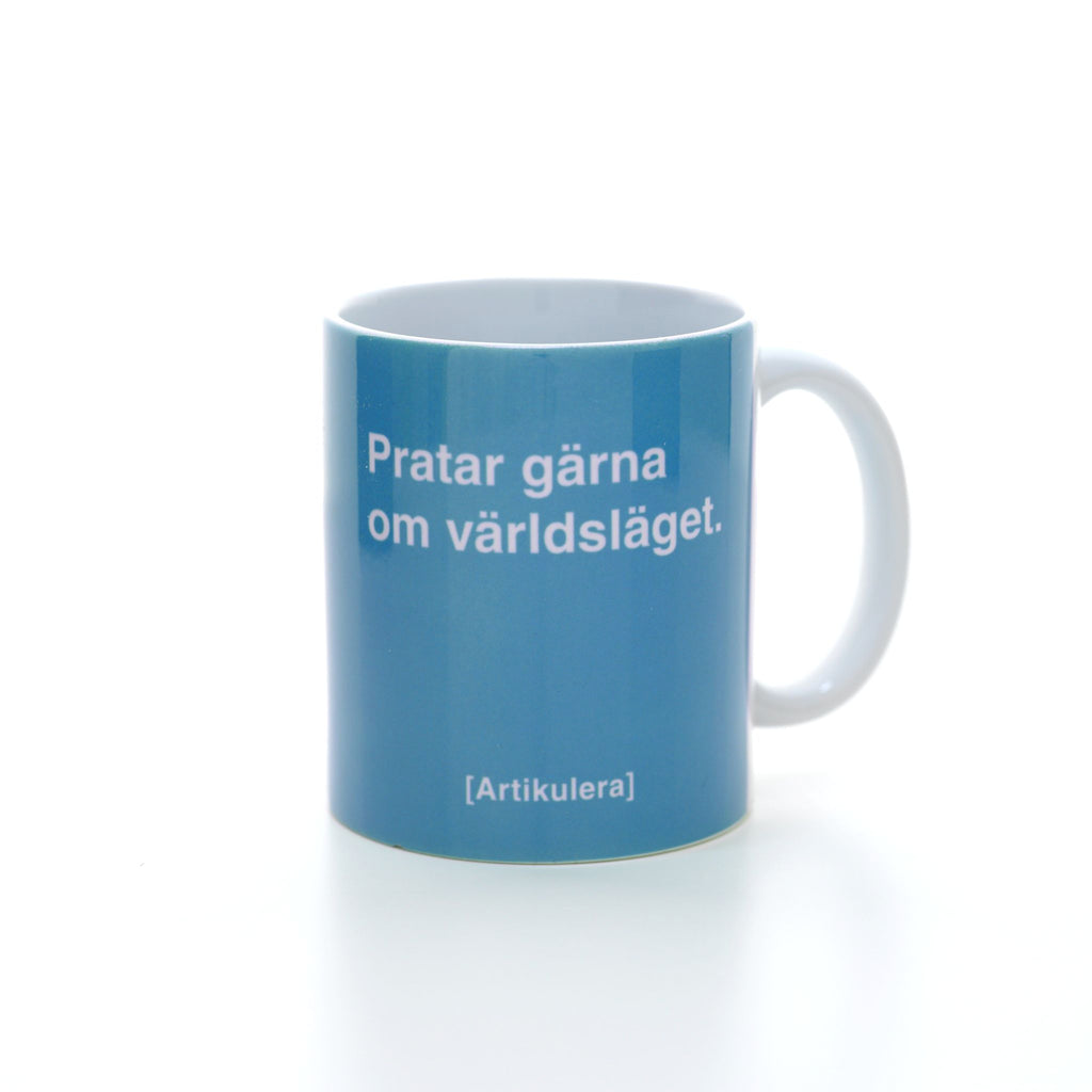 Vit mugg med ljusblått tryck, vit text ”Pratar gärna om världsläget.” samt vit Artikulera-logotyp