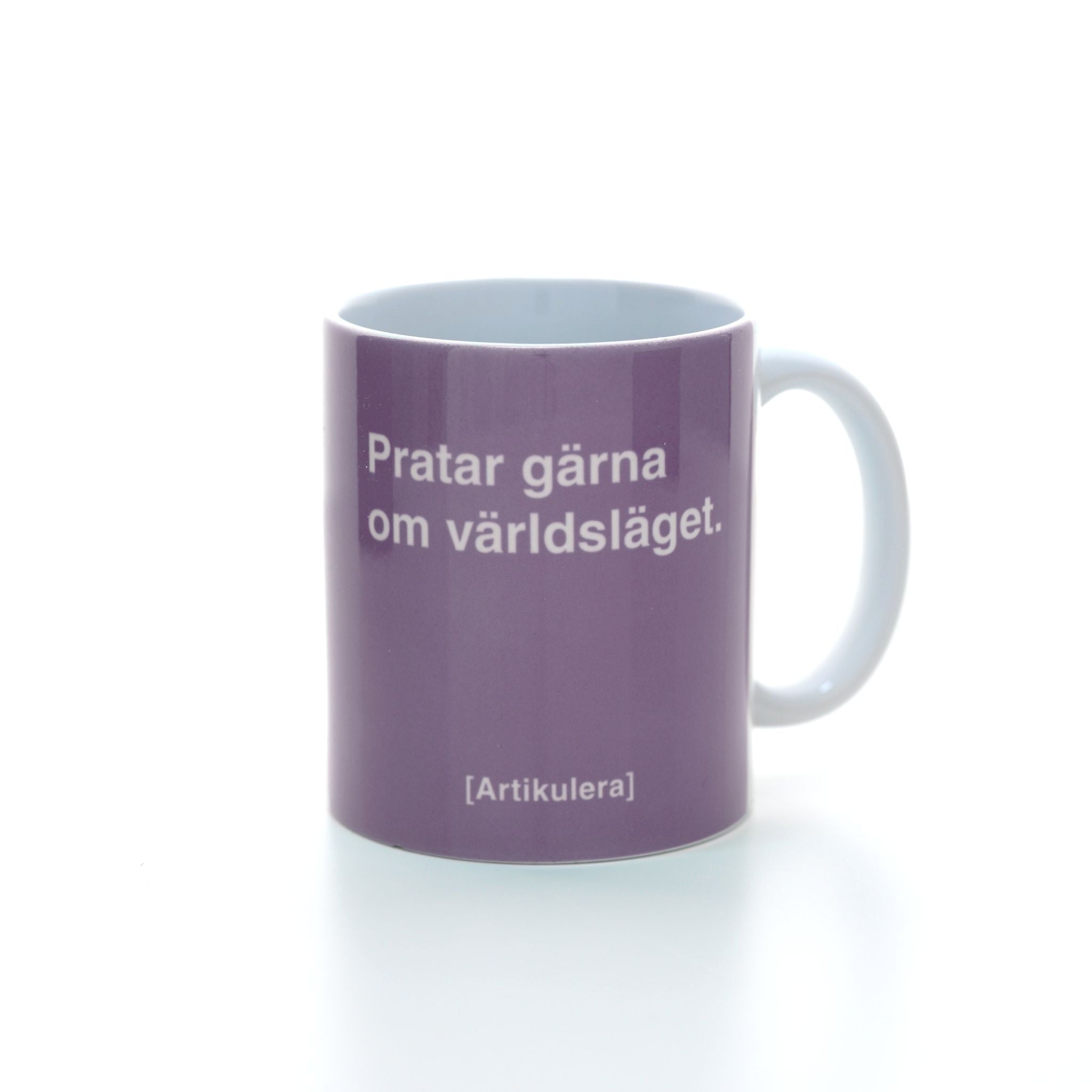 Vit mugg med ljuslila tryck, vit text ”Pratar gärna om världsläget.” samt vit Artikulera-logotyp