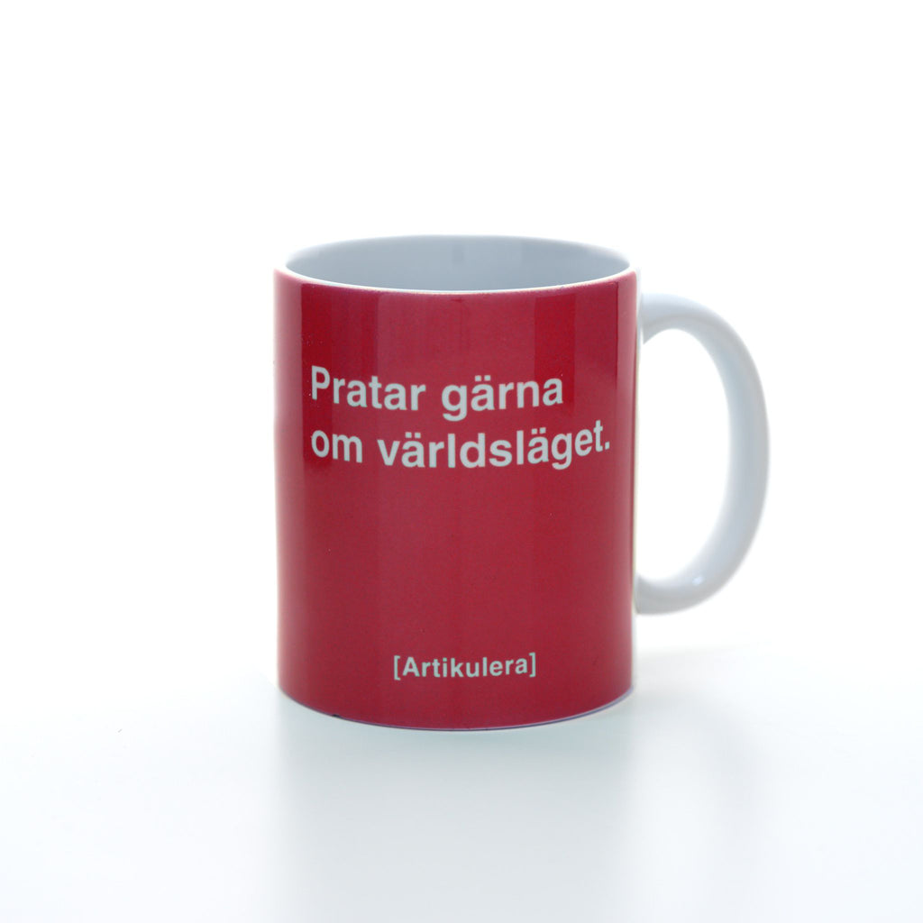 Vit mugg med magentarött tryck, vit text ”Pratar gärna om världsläget.” samt vit Artikulera-logotyp
