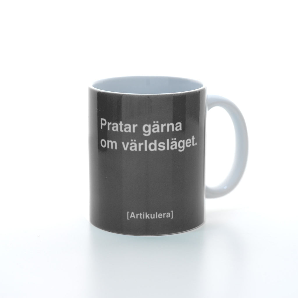 Vit mugg med mörkt rockigt grått tryck, vit text ”Pratar gärna om världsläget.” samt vit Artikulera-logotyp