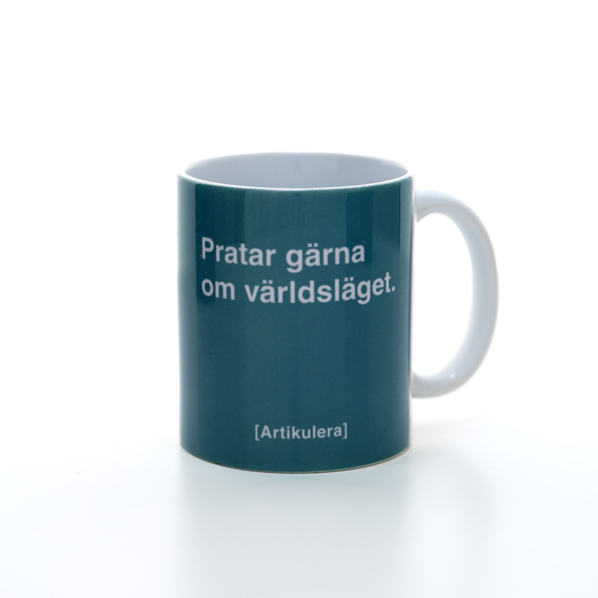Vit mugg med mörkt turkosgrönt tryck, vit text ”Pratar gärna om världsläget.” samt vit Artikulera-logotyp