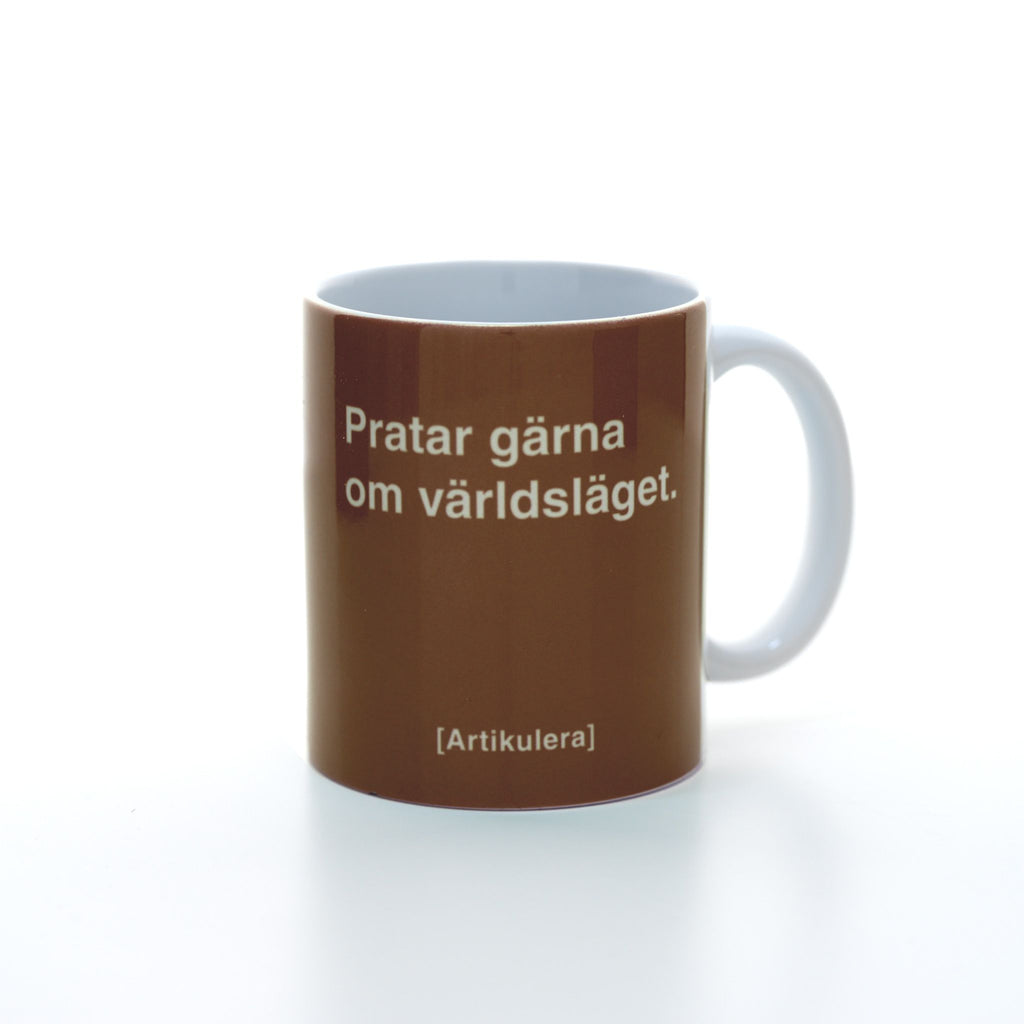 Vit mugg med mörkbrunt tryck, vit text ”Pratar gärna om världsläget.” samt vit Artikulera-logotyp