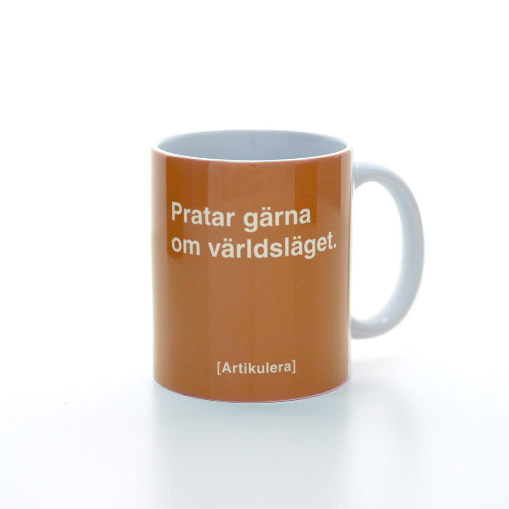 Vit mugg med orange tryck, vit text ”Pratar gärna om världsläget.” samt vit Artikulera-logotyp