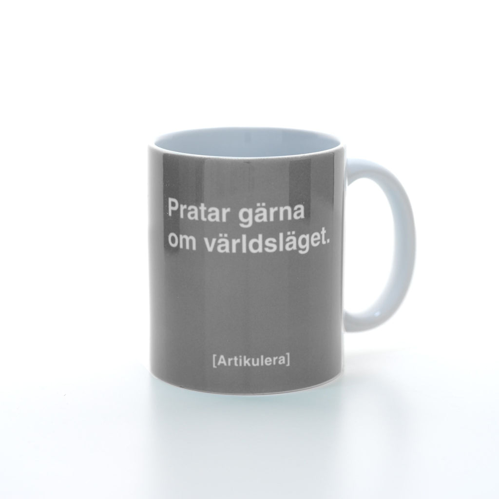 Vit mugg med rockigt grått tryck, vit text ”Pratar gärna om världsläget.” samt vit Artikulera-logotyp