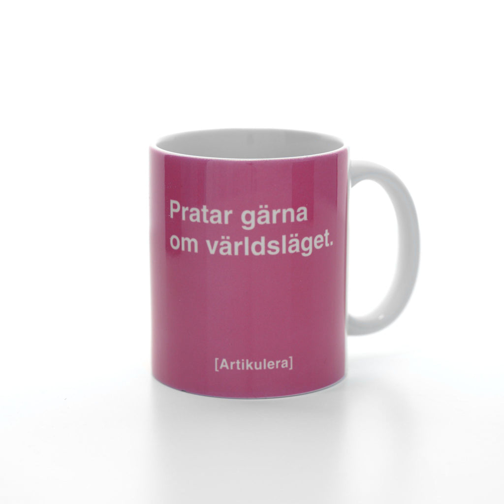 Vit mugg med rosa tryck, vit text ”Pratar gärna om världsläget.” samt vit Artikulera-logotyp