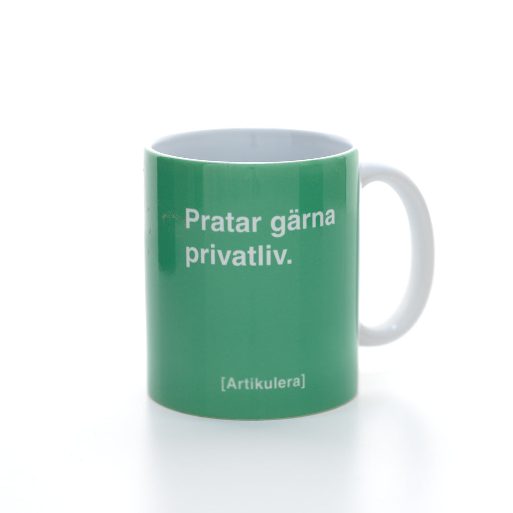 Vit mugg med grönt tryck, vit text ”Pratar gärna privatliv.” samt vit Artikulera-logotyp