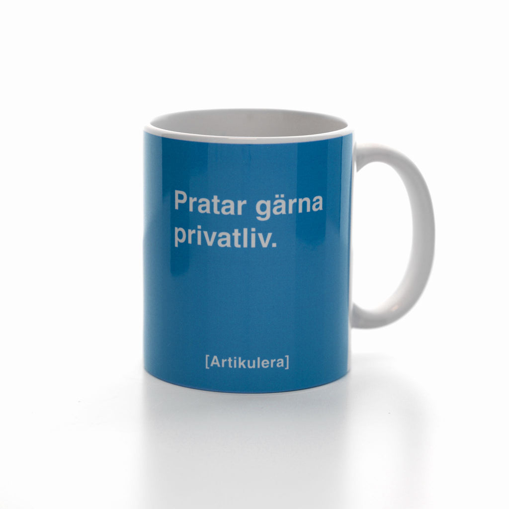Vit mugg med himmelsblått tryck, vit text ”Pratar gärna privatliv.” samt vit Artikulera-logotyp