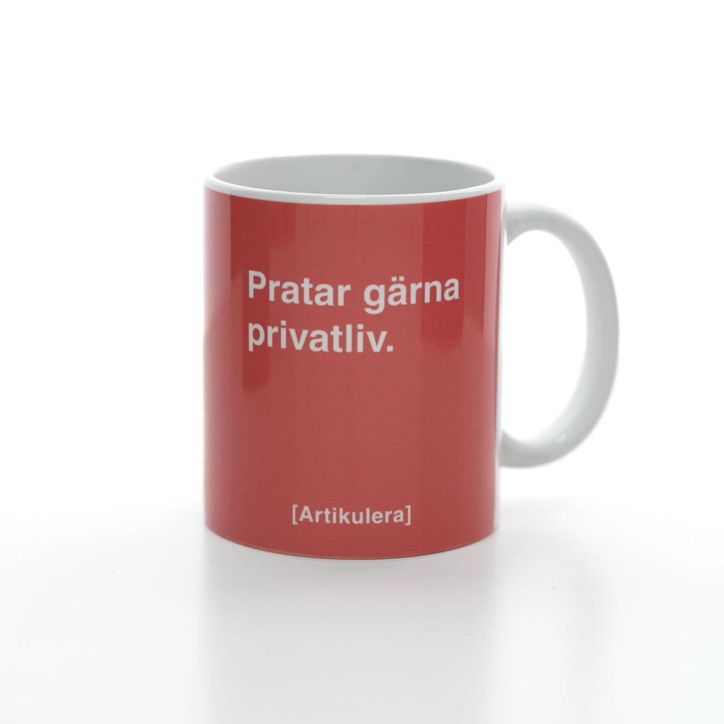 Vit mugg med korallrött tryck, vit text ”Pratar gärna privatliv.” samt vit Artikulera-logotyp