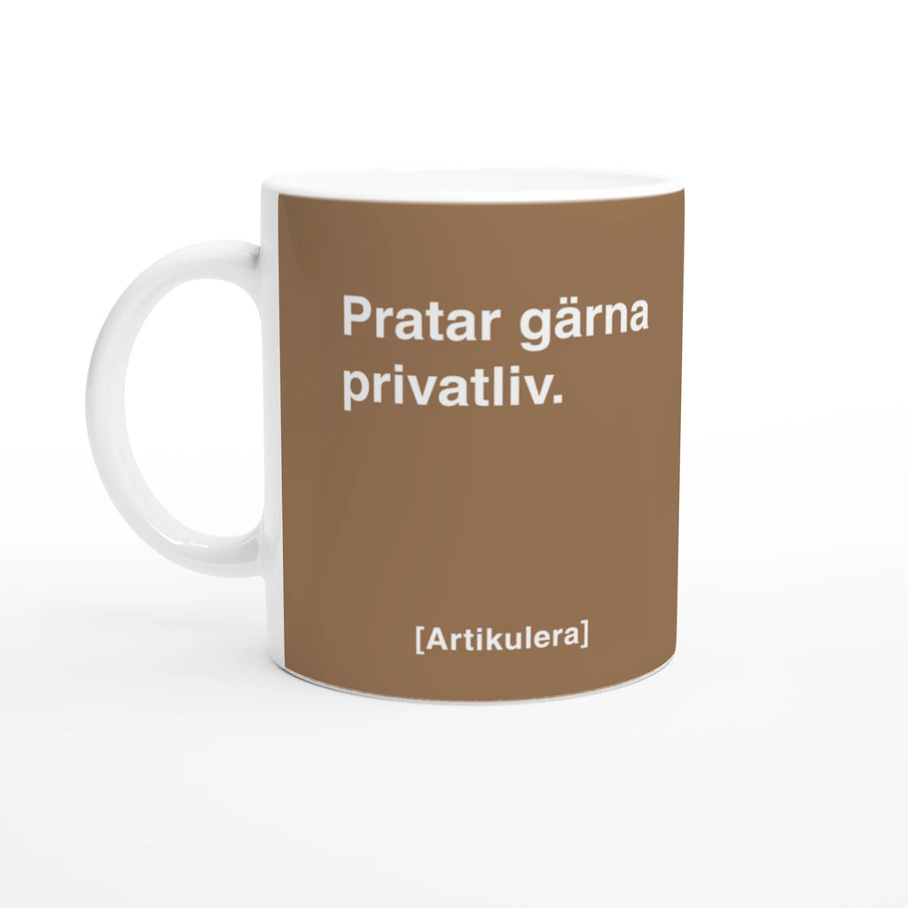 Vit mugg med mediumbrun tryck, vit text ”Pratar gärna privatliv.” samt vit Artikulera-logotyp