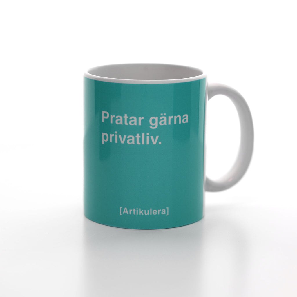 Vit mugg med ljust blågrönt tryck, vit text ”Pratar gärna privatliv.” samt vit Artikulera-logotyp