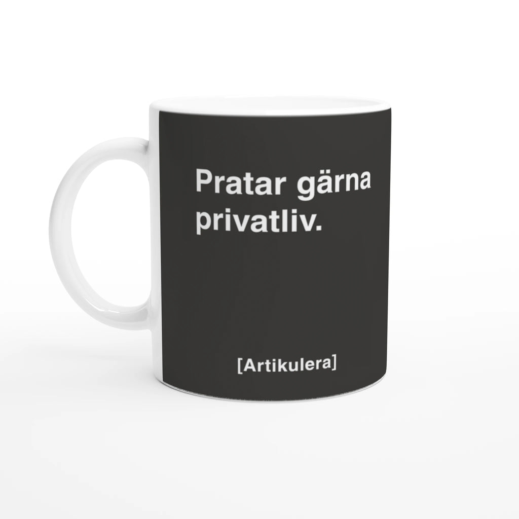 Vit mugg med mörkt rockigt grått tryck, vit text ”Pratar gärna privatliv.” samt vit Artikulera-logotyp