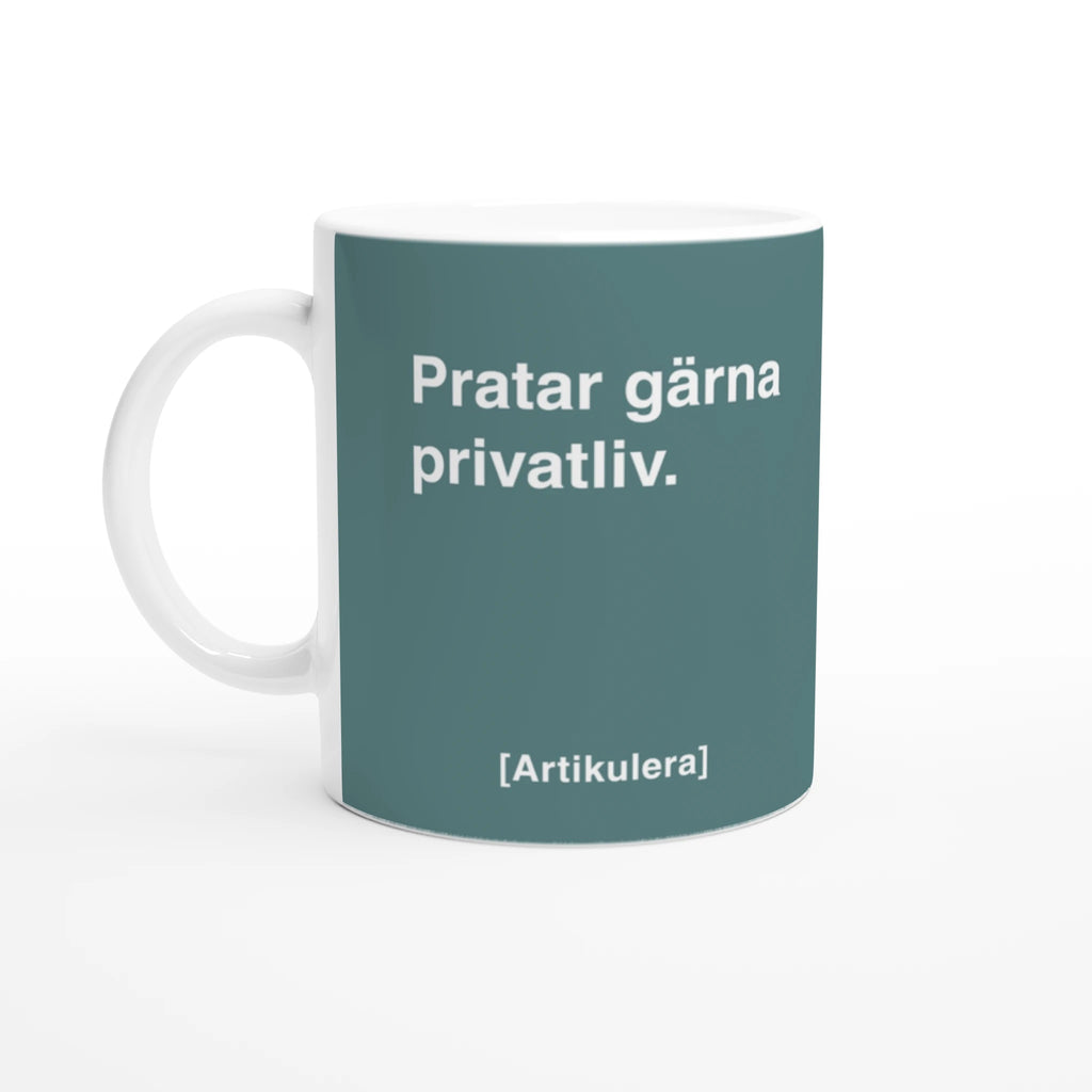 Vit mugg med mörkt turkosgrönt tryck, vit text ”Pratar gärna privatliv.” samt vit Artikulera-logotyp