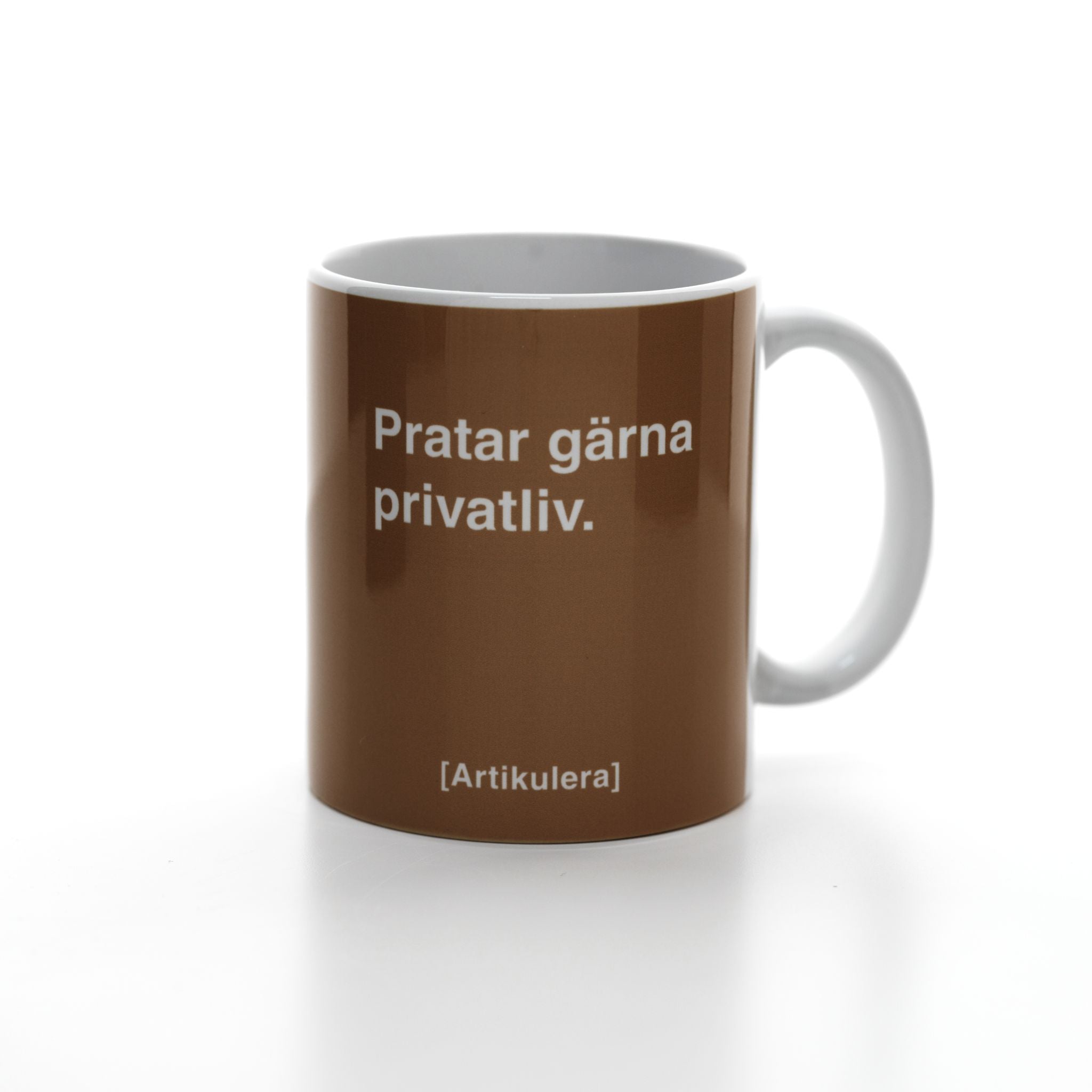 Vit mugg med mörkbrunt tryck, vit text ”Pratar gärna privatliv.” samt vit Artikulera-logotyp
