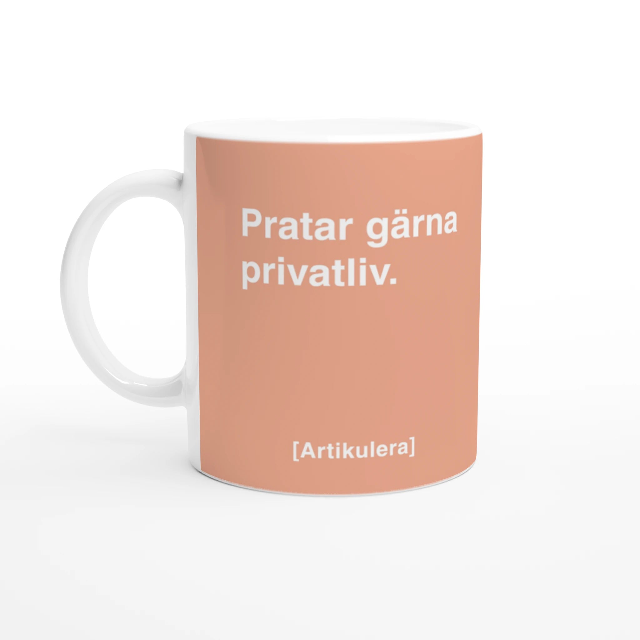 Vit mugg med persikofärgat tryck, vit text ”Pratar gärna privatliv.” samt vit Artikulera-logotyp