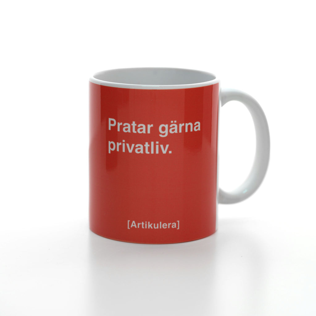 Vit mugg med tomatrött tryck, vit text ”Pratar gärna privatliv.” samt vit Artikulera-logotyp